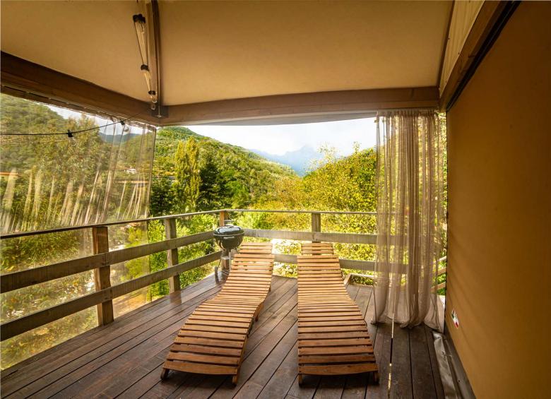 Terrasse mit Holzliegen und Bergblick.